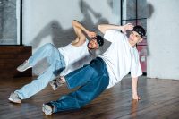 spotlight on handsome multicultural dancers in headbands posing while dancing hip-hop
